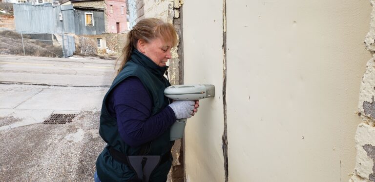 A BEC Environmental Scientist uses an XRF Spectrometer to analyze the paint on the side of a brownfield building for lead content