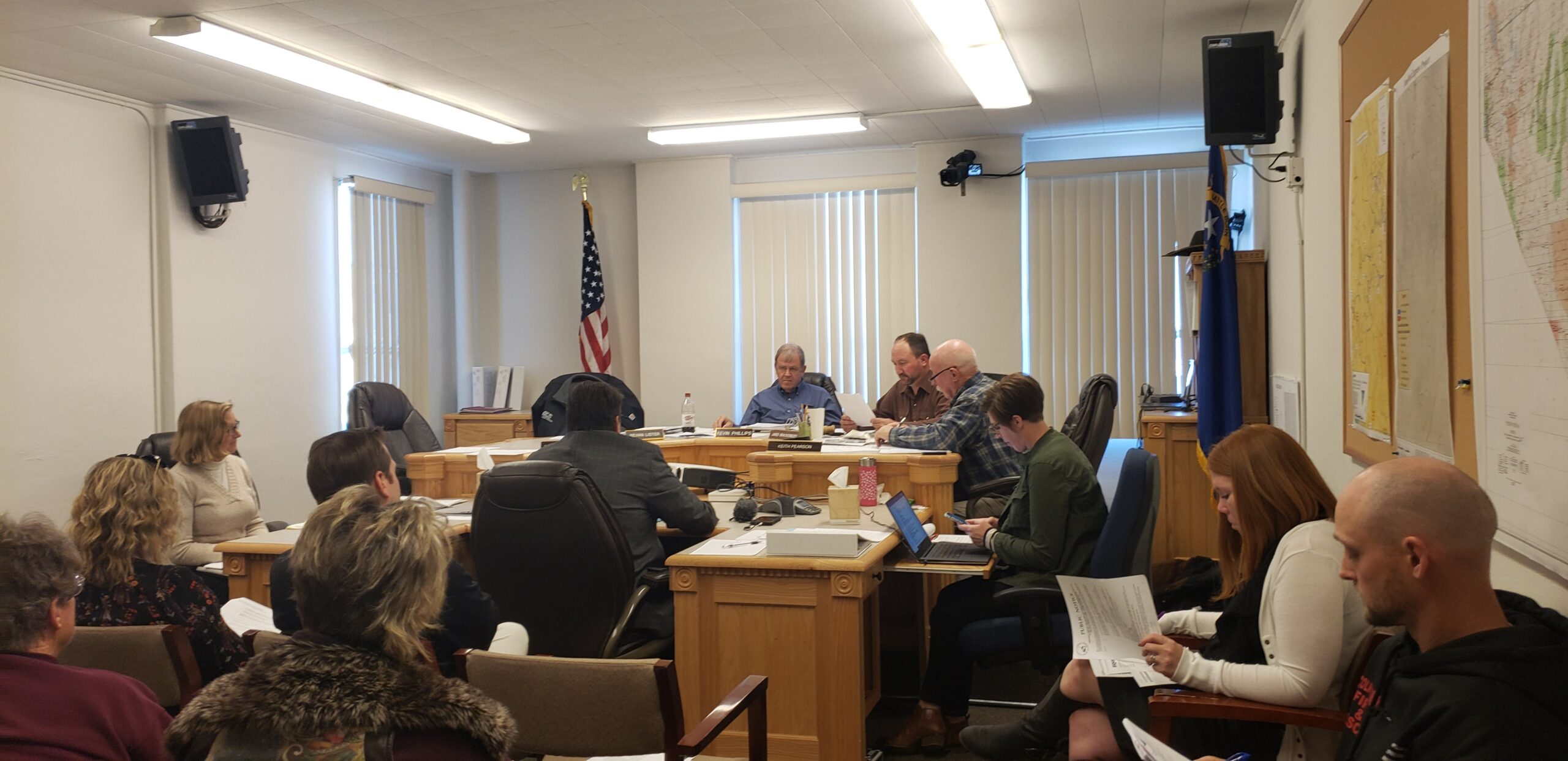 A Board of County Commissioners meeting with the board listening to a speaker taking place in a rural Nevada office.